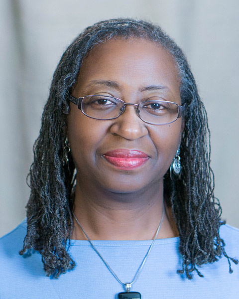 A head shot of Beverly Moss, an African-American woman, early 60s, in a light blue sweater, looking straight at the camera