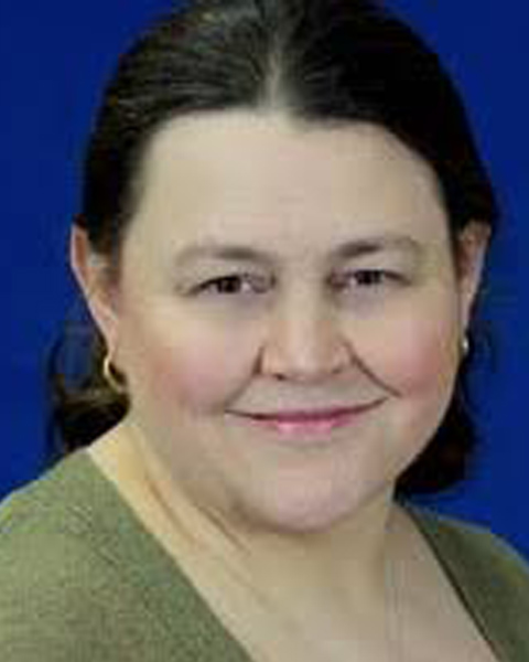 A headshot of Heather Robideaux from the shoulders up smiling in a green shirt and gold hoop earrings