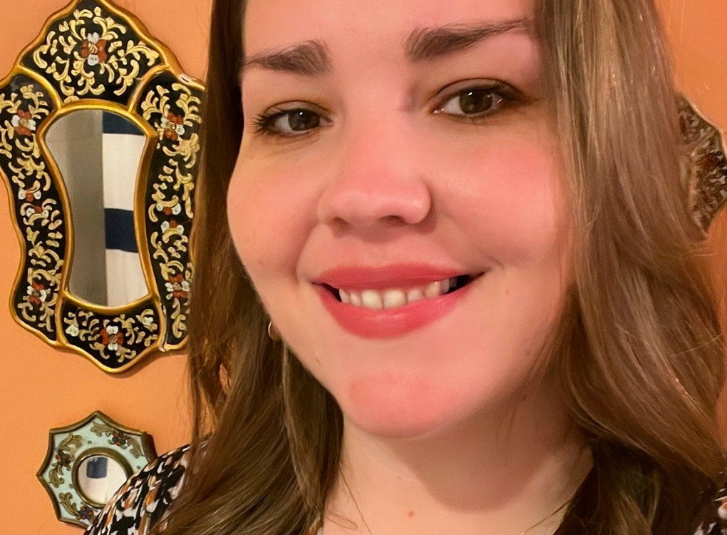 Dr. Laura Gonzales, a light-skinned woman with brown hair, wearing a black, brown, and white patterned top.