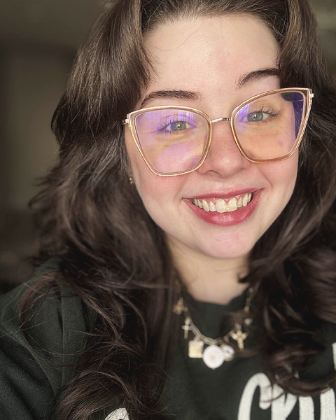 Jami Padgett, a white femme-presenting person with dark hair and glasses, smiling.