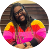 Eric Darnell Pritchard, a black person wearing a rainbow dress while sitting on wooden stairs